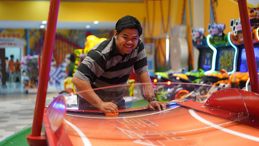 Guest enjoying arcade air hockey at Jump Around Now indoor trampoline park in Chula Vista, CA